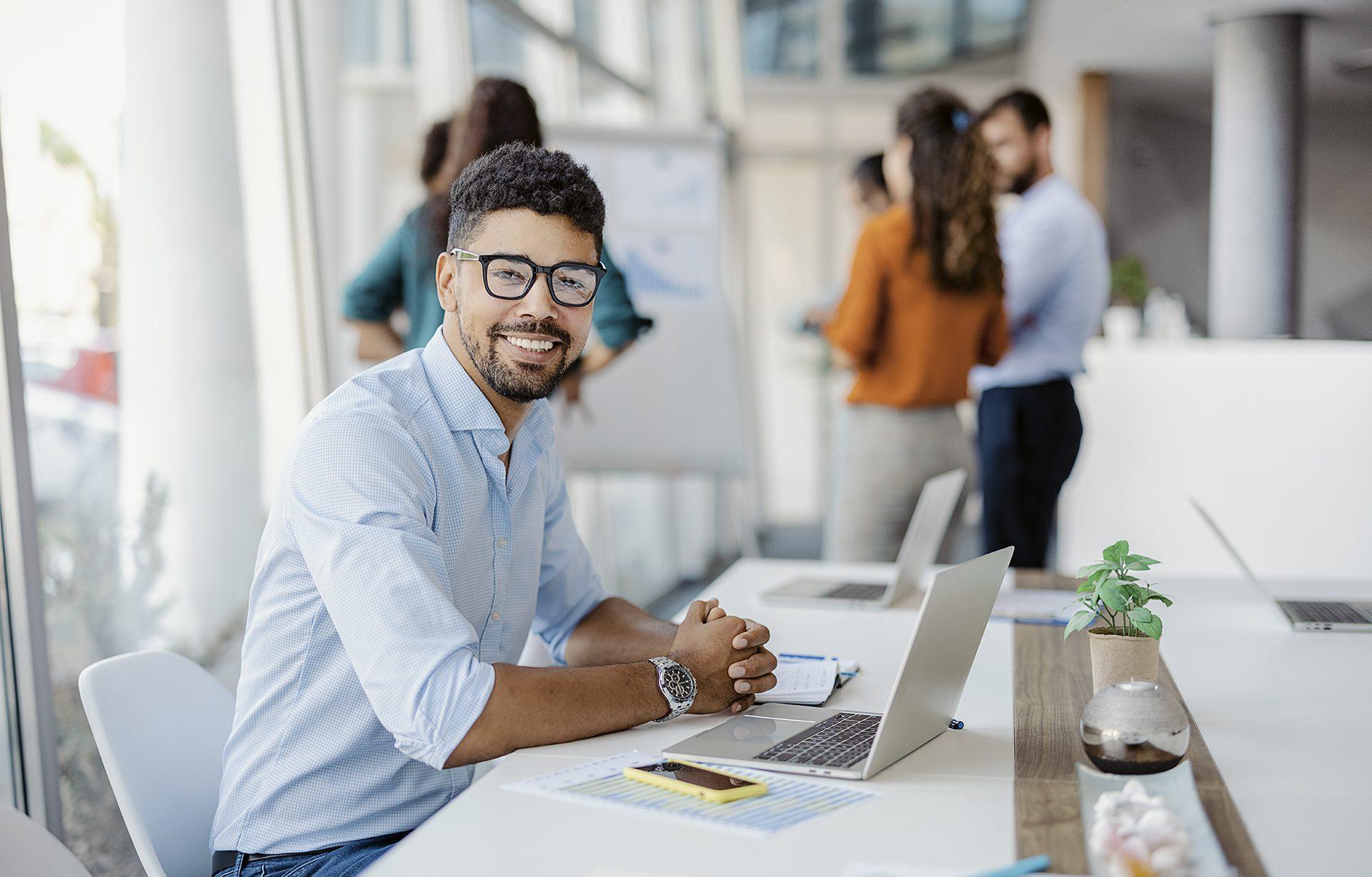 Man working in office with colleagues in the background